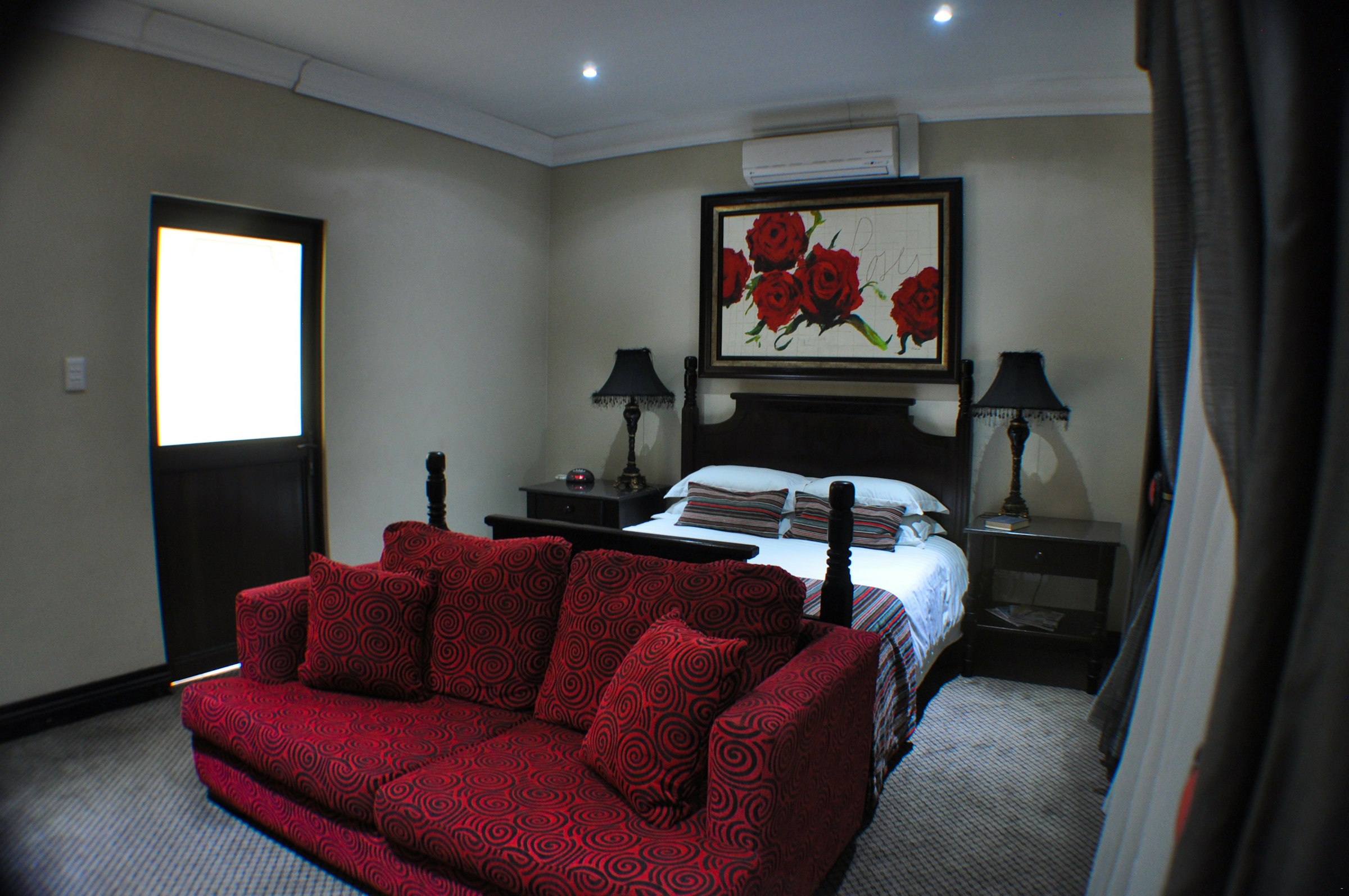 Elegantly appointed bedroom suite with red lounge seating at Au Jardin Guesthouse